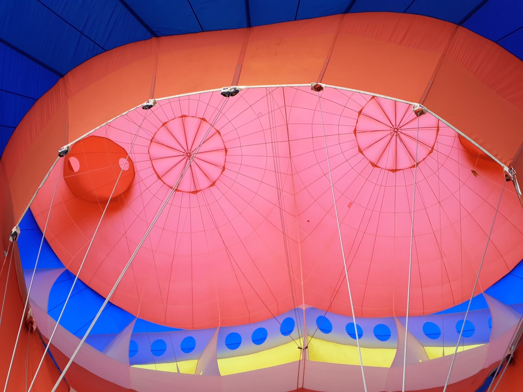 Looking into the mouth of the balloon at the twin parachutes at the top of the red heart. To the left of the left parachute is the opening for the hand. 